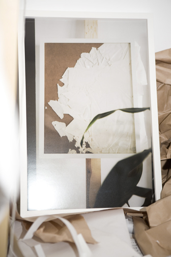 Framed print with torn and folded white paper layered across its surface